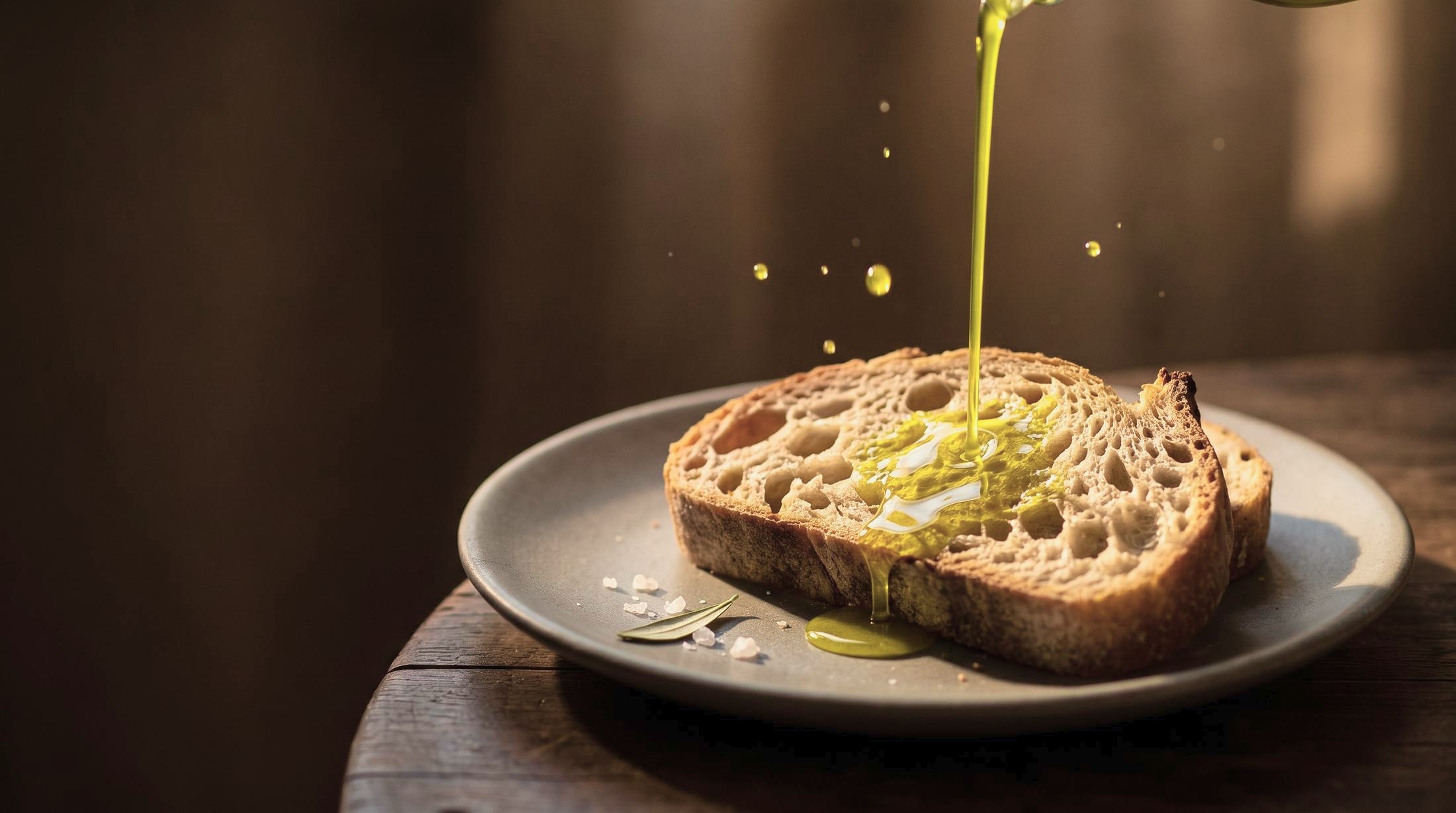 Azeite extravirgem verde-dourado escorrendo sobre uma fatia de pão de fermentação natural